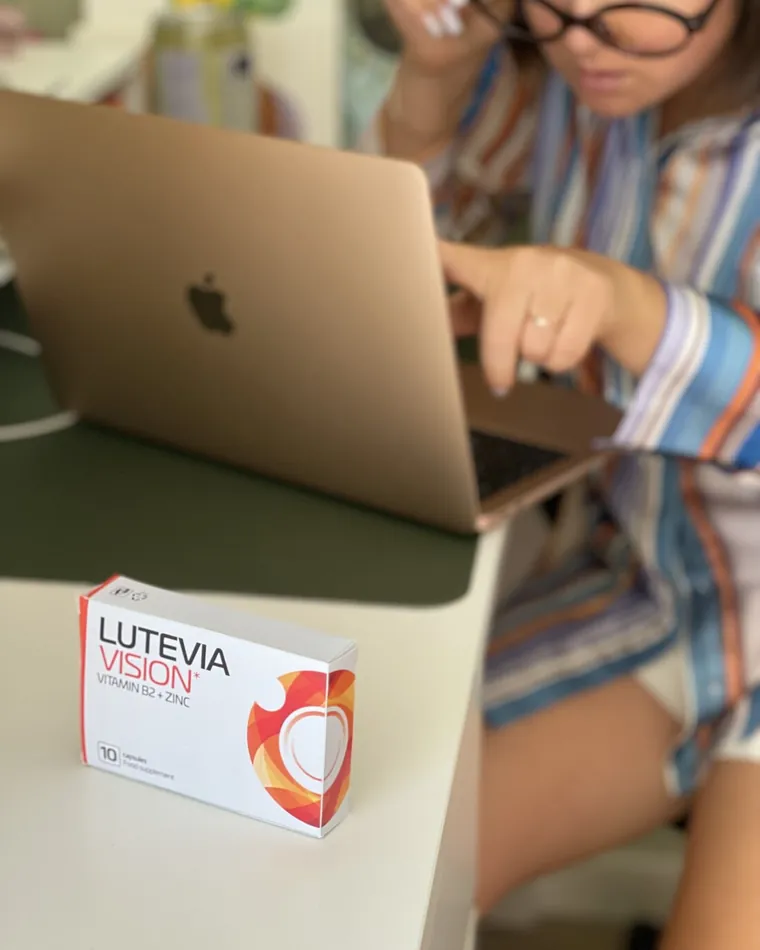 Mujer trabajando con el portátil y una caja de Lutevia Vision sobre la mesa